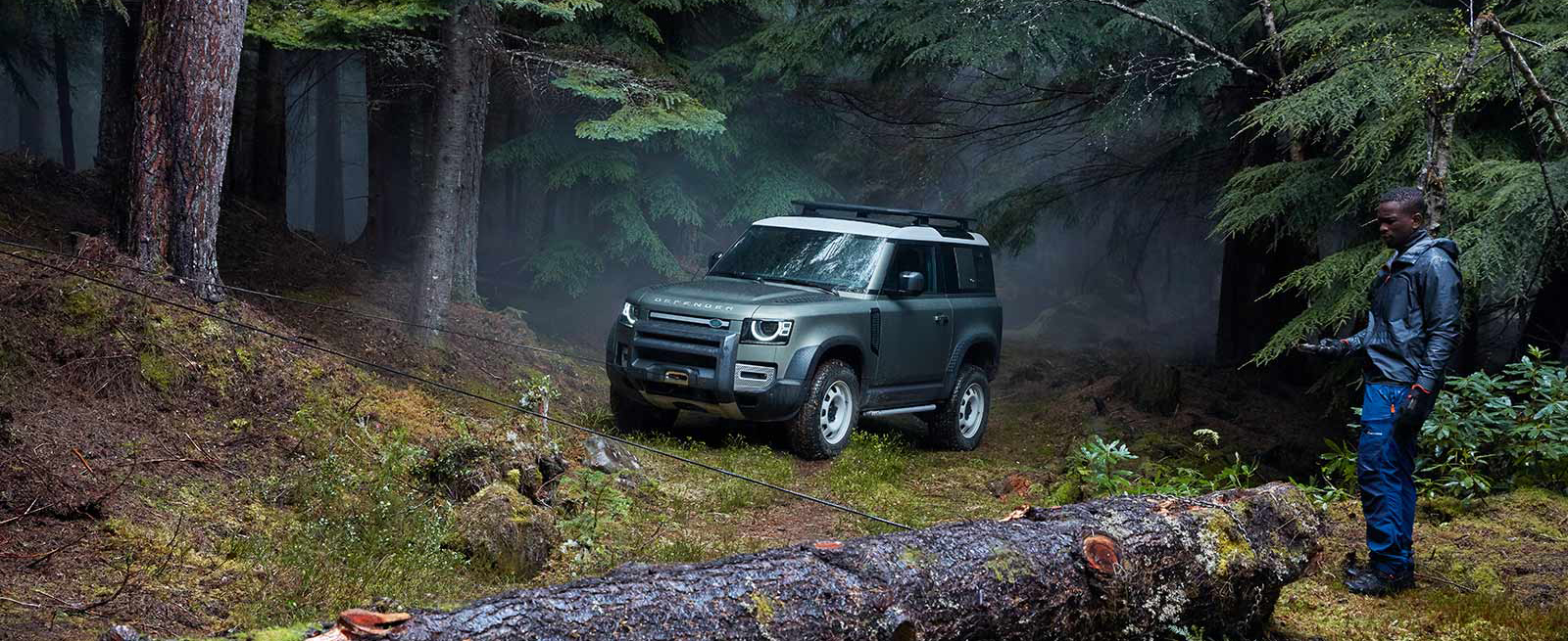 Green New Defender 90 Using Front Winch in a Forest