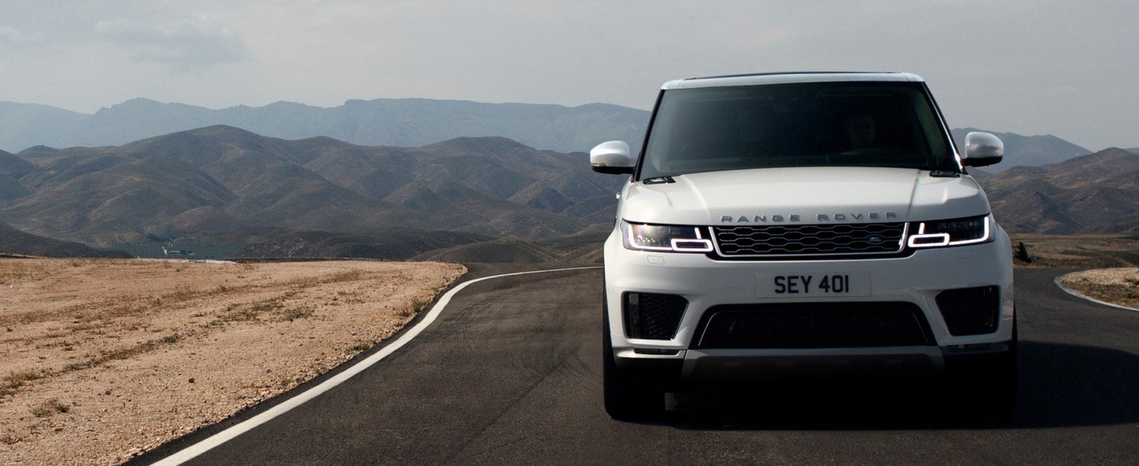 White Range Rover Sport Driving Through A Desert Road